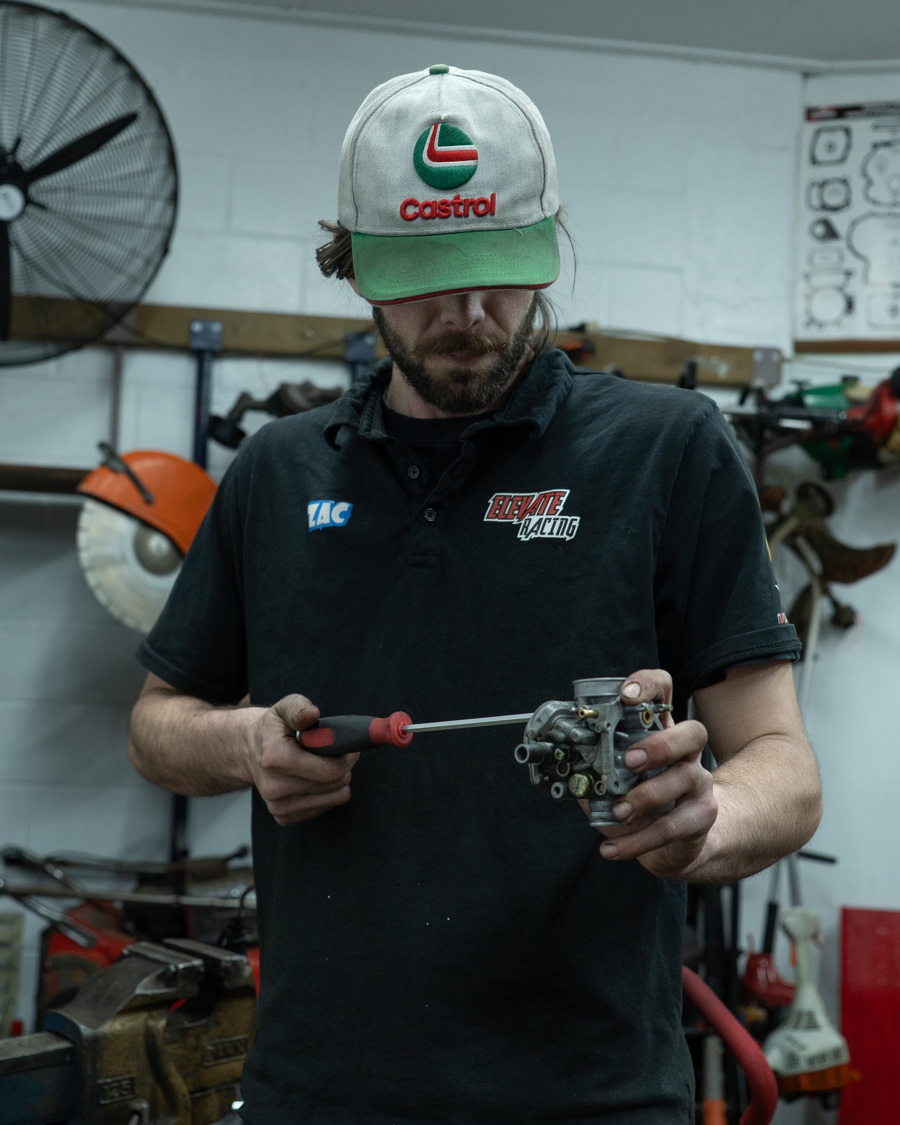 A mechanic holding a stripped-down carburetor in a Wellington workshop.